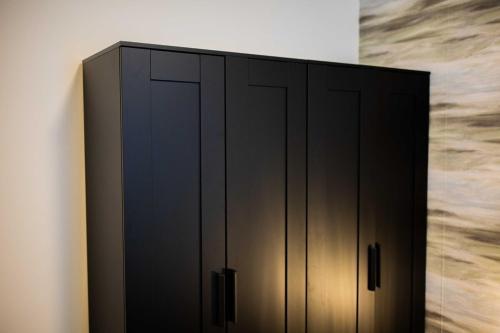 a black cabinet with black doors in a room at Stylish 50m2 Two-Bedroom Apartment - SD23K in Eindhoven