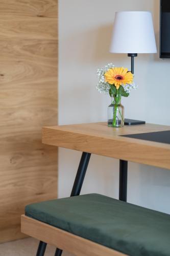 a vase of flowers sitting on a desk with a lamp at Hotel Die Pflegerbrücke in Salzburg