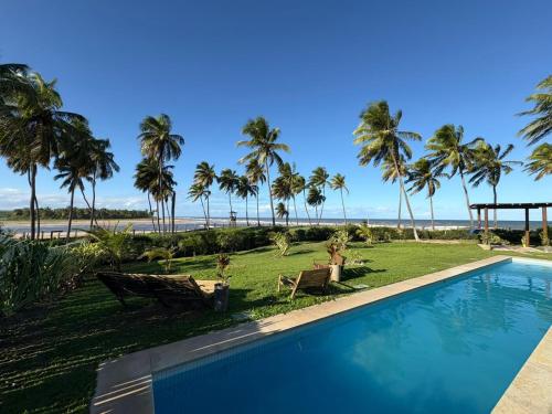 バイシオにあるBeach house - secured, beach access, sea view, best locationのヤシの木が茂るビーチのそばのスイミングプール