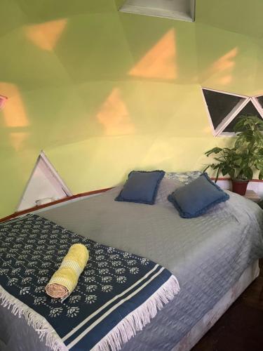 a bedroom with a bed with blue pillows at Domos Temuco, Cumbres del Conunhuenu in Temuco