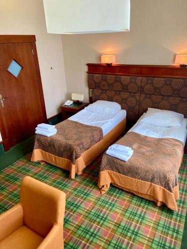 a hotel room with two beds and a chair at Hotel Wawrzyniak in Zduny
