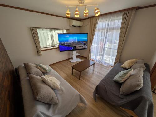 a living room with two beds and a flat screen tv at Villa Ishiba-Otsu by Kyoto ヴィラ石場大津 by 京都 in Otsu
