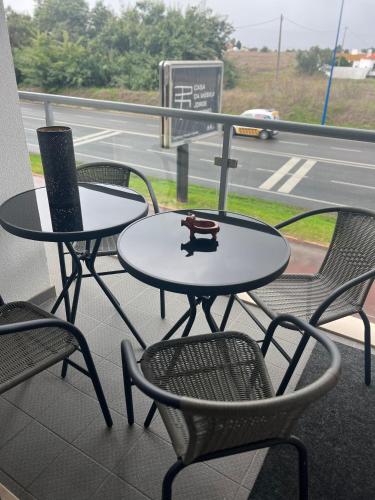 two tables and chairs on a balcony with a street at Modern Big Room with Balcony in New Apartment in Montijo