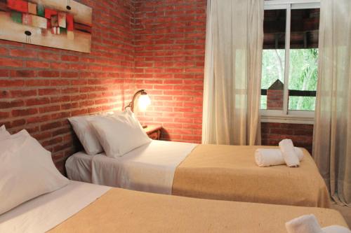 two beds in a room with a brick wall at Carilo Village Apart Hotel & Spa in Carilo