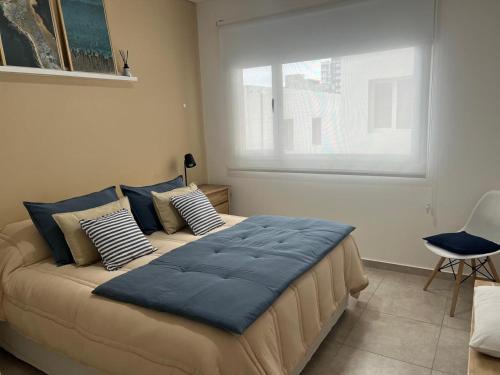 een groot bed met blauwe kussens in een slaapkamer bij Departamento Venthos in Puerto Madryn