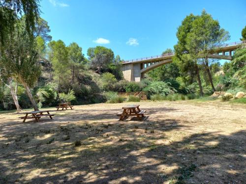three picnic benches in a park with a bridge in the background at Casa rio gallego in Gallego