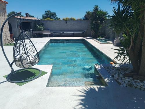 Una piscina con un columpio en un patio. en Villa Besne, en Thuir