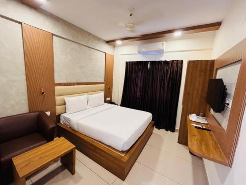 a bedroom with a bed and a chair and a television at Hotel Rotano Garden Near Marathahalli Bridge in Bengaluru