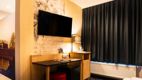 a hotel room with a desk and a television on the wall at Altora Eisenbahn Themenhotel in Wernigerode