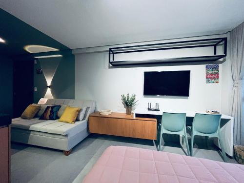 a living room with a couch and a table and a tv at Flat Lindo e Espaçoso com Varanda e Vista Mar in João Pessoa