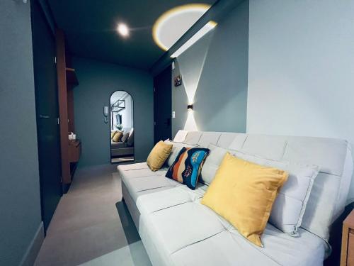 a living room with a white couch with pillows on it at Flat Lindo e Espaçoso com Varanda e Vista Mar in João Pessoa
