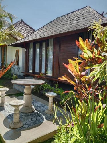 a garden with a table and a house at Uma Desa - Surf And Stay Medewi in Airsatang