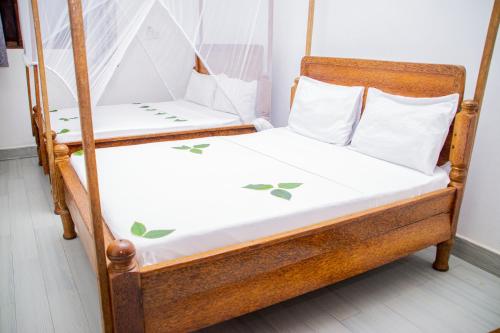 a wooden bunk bed with white sheets and green leaves at Amazing Beach Hotel Zanzibar in Nungwi