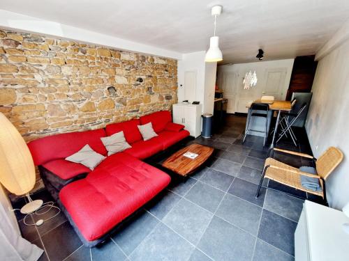 ein rotes Sofa im Wohnzimmer mit Ziegelwand in der Unterkunft Duplex central à Lyon pour 5 personnes in Lyon
