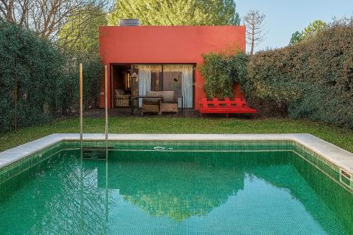 Una piscina con un banco rojo y una casa roja. en Hotel Boutique Pinar by Bossh! Hotels, en Cuenca
