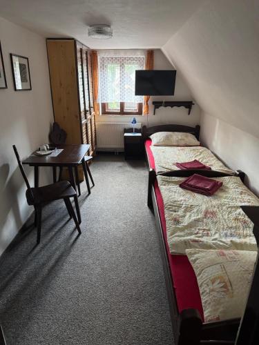 a bedroom with a bed and a table and a desk at Penzion Dřevák in Jetřichovice