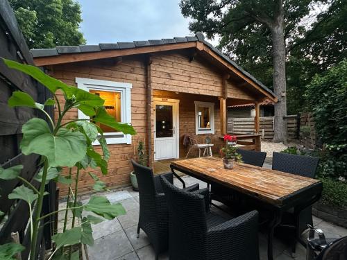 a small cabin with a wooden table and chairs at Veluws vakantiehuisje Kawoeper Lodge in Ermelo