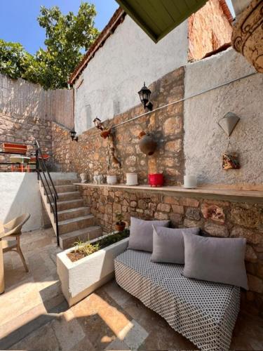 a patio with a wicker bench and a stone wall at Taş Bahçe in Ayvalık