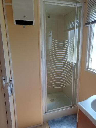 a glass shower in a bathroom next to a sink at Ferme de ussau in Betchat