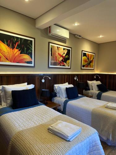 a hotel room with three beds with towels on them at Pousada das Lavandas in Campos do Jordão