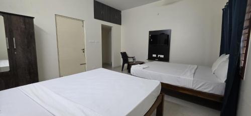 a hotel room with two beds and a tv at RJ Residency Srirangam in Tiruchchirāppalli