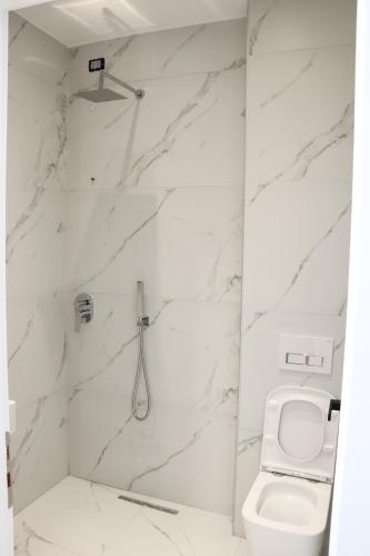 a white bathroom with a toilet and a sink at Joni`s Guesthouse in Shkodër