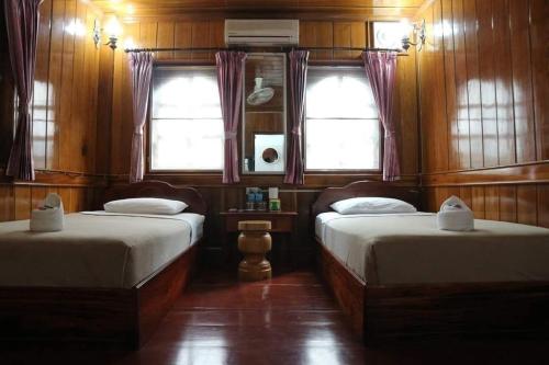 琅勃拉邦3 days tour to visit surroundings of Luang Prabang的房间里有两张床，墙壁和窗户都是木制的