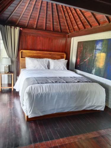 a bedroom with a large bed with a wooden headboard at Uma Desa - Surf And Stay Medewi in Airsatang