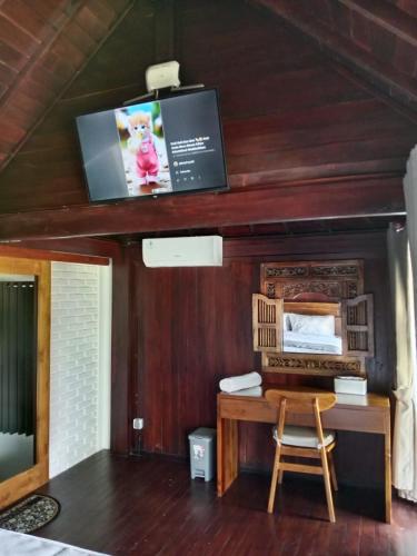 a room with a desk and a tv on the ceiling at Uma Desa - Surf And Stay Medewi in Airsatang