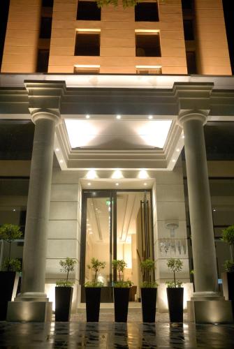 a building with columns and potted plants in front of it at Premium Tower Suites Mendoza in Mendoza