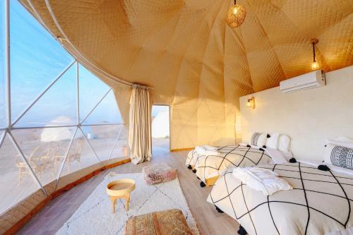 two beds in a room with a large window at The Orion Dome in El Karia