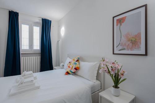 a bedroom with a white bed with a vase of flowers at Italian Experience- Aselli Home in Pavia