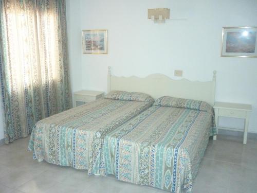 łóżko w sypialni z 2 stołami i narzutą w obiekcie Apartamentos Jorbar w El Arenal