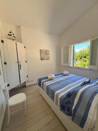 a bedroom with a bed and a chair and a window at Marilù Casa Vacanza in San Vito lo Capo
