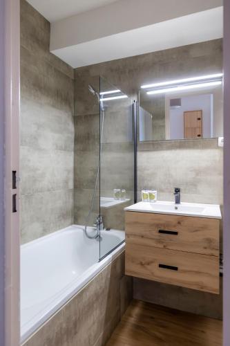 une salle de bain avec une baignoire, un lavabo et une douche dans l'établissement Mas de Blais appartement Chaleureux à 5 minutes des pistes, à Briançon