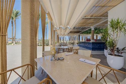a restaurant with a table and chairs and palm trees at Grand Makadi - Couples and Families Only in Hurghada