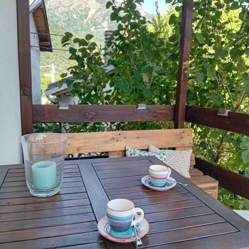 a wooden table with two cups and a glass of water at Scola veja in Chianocco