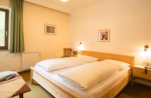 a bedroom with a large bed with white sheets at Berghotel Kason in Predoi