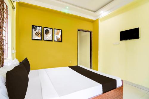 a bedroom with a white bed and a yellow wall at Hotel O TARA in Jojera