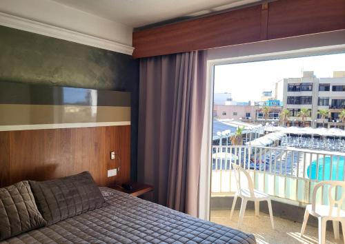 a bedroom with a bed and a balcony with a view at Topaz Hotel in St Paul's Bay