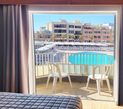 a balcony with two chairs and a swimming pool at Topaz Hotel in St Paul's Bay
