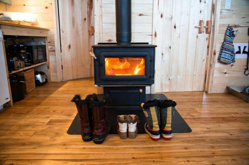 a stove with a group of boots in a room at Huttopia Les Deux Lacs - Laurentides in Mont-Blanc