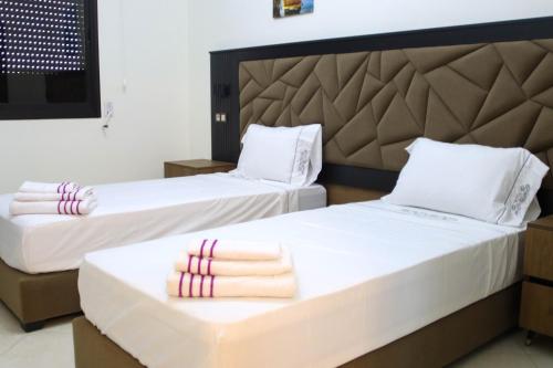 two beds in a hotel room with towels on them at Larache haut standing in Larache
