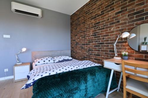 une chambre avec un mur de briques, un lit et un bureau dans l'établissement Apartament #CapitalTower 167 FV PARKING, à Rzeszów