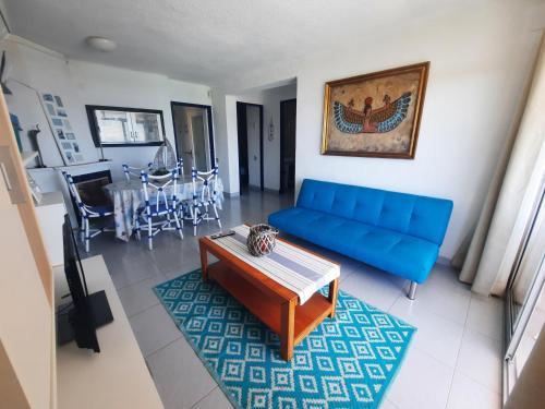 een woonkamer met een blauwe bank en een tafel bij Apartamento Palmeras in La Pineda