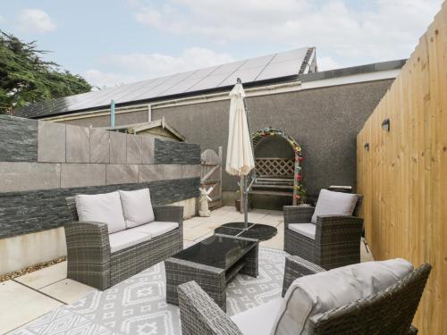 a patio with wicker furniture and an umbrella at 76A Mackworth Road in Porthcawl
