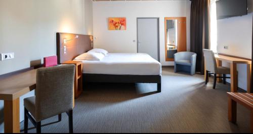 a hotel room with a bed and a desk and chairs at Hôtellerie Notre Dame de Lumières in Goult