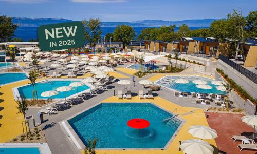 an aerial view of a resort with two pools and umbrellas at Aminess Style Glamping Villas & Holiday Homes Atea in Njivice
