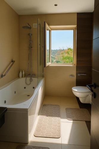 a bathroom with a tub and a toilet and a window at Golf - Vale Da Pinta T2 com Piscina, Wi-Fi e Ar Condicionado in Carvoeiro