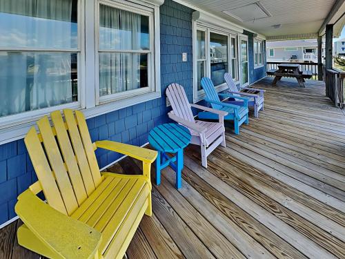 a porch with rocking chairs and a table on a house at On Island Time in Topsail Beach